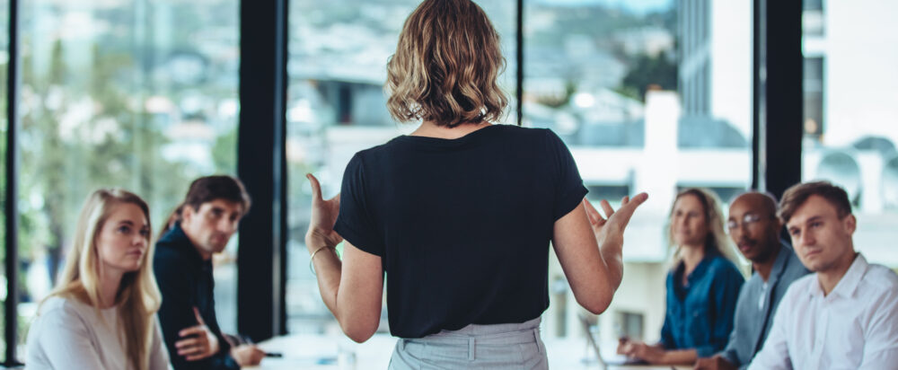 Rear,View,Of,A,Woman,Explaining,New,Strategies,To,Coworkers