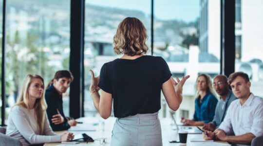 Rear,View,Of,A,Woman,Explaining,New,Strategies,To,Coworkers