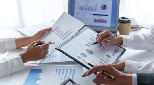 Business,People,Point,To,Graph,And,Chart,To,Analyze,Market