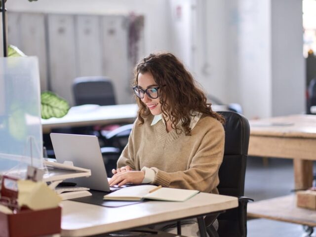 Young,Happy,Professional,Business,Woman,Employee,Sitting,At,Desk,Working